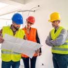 Ingenieur, architect en klant bekijken blauwdrukken op bouwplaats.