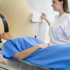 Vrouwelijke patiënt van middelbare leeftijd wordt begeleid door verpleegster voor scan.