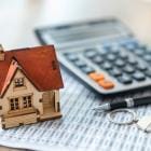 Concept van miniatuurhuis naast rekenmachine en cijfermateriaal.