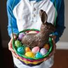 Close-up van kinderhanden die een paasmand vol lekkers vasthouden.