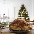 Gebraden kalkoen met kerstboom op de achtergrond.