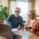 Ouder koppel doet papierwerk en gebruikt laptop.