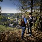 2 mannen bekijken kaart tijdens wandeling met uitzicht over dorp omringd door natuur.