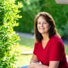 Vrouw van middelbare leeftijd zit op een bank in de zonnige tuin.