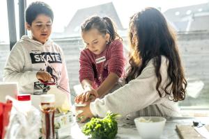 Mohammed Ali, Alexandra en Zyneb zijn druk bezig met ‘gras’ (lees: gehakte bieslook) te maken om hun aperitiefplank af te maken.