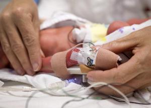 Archieffoto, verpleegkundige controleert het infuus in de hand van een te vroeg geboren, prematuur, kind dat in een couveuse ligt.