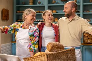 Camille Dhont samen met Katelijne Verbeke en Mathijs Scheepers, die haar oma en vader spelen in de telenovelle ‘Milo’ in het eerste decor van de reeks: de bakkerij van Milo’s vader Pol.