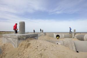 Groep mensen ontdekken betonnen kunstinstallatie op strand van Zee-Brugge