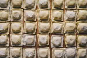 Raw traditional Italian ravioli with flour,Basil,Egg,And salt on a wooden board