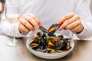 Man eating mussels with white wine in a seafood restaurant, close-up view