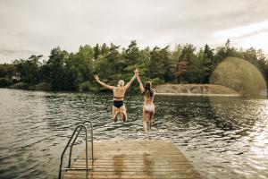 Rear view of female friends wearing bikini while jumping in lake during vacation