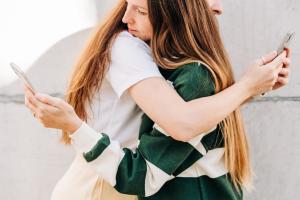 People live on social networks. Two people using phone at the street.