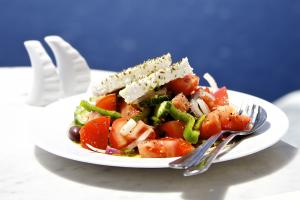 Greek salad on white plate in front of sea.