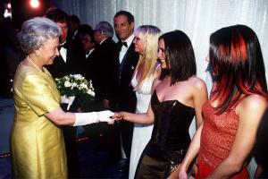 Le 1er décembre 1997, la reine ELizabeth II serre la main de la pop star Victoria Beckham (posh Spice) du groupe pop The Spice Girls