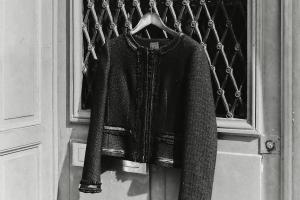 Zwart-wit foto van een deur. Aan de deur hangt een kledinghanger met een zwart vintage vest.