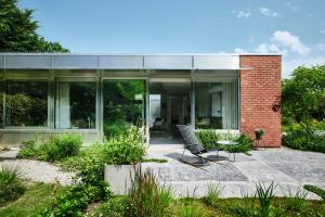 Magazijn in rode baksteen wordt architecturale zorgwoning. De gerecupereerde terrastegels lagen in een vorig leven voor de ingang van een kerk. ‘Duizenden mensen hebben er jarenlang over gewandeld, nu spelen onze kleinkinderen erop.’