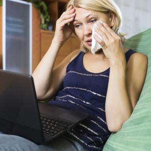 Woman crying while using laptop