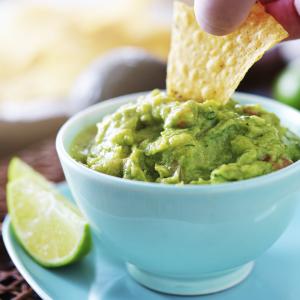 eating guacamole with tortilla chip from bowl
