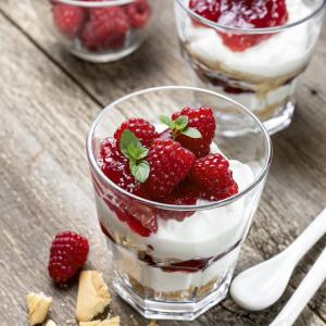 cheesecake with raspberries, mint in glass on old wooden background