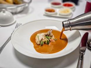 Pouring the lobster bisque into the bowl.