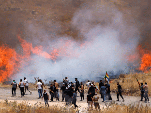 Leden van de Druzen-gemeenschap in Syrië lopen door traangas dat is afgevuurd door Israëlische troepen om hen uiteen te drijven, terwijl ze zich op 16 juli 2025 verzamelen langs de scheidingslijn in een poging het prikkeldraadhek over te steken naar de door Israël geannexeerde Golanhoogten nabij Majdal Shams. Israëlische soldaten probeerden die dag de menigte onder controle te houden en te verhinderen dat Druzen de grens met Syrië overstaken, na dodelijk geweld in het zuiden van het land dat Damascus ertoe aanzette regeringstroepen te sturen.