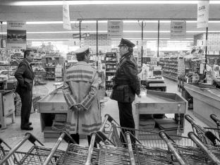 Brute overval op supermarkt Delhaize door De Bende van Nijvel, ook bekend als les Tueurs du Brabant of De dolle schutters van Waals Brabant, is de bekendste criminele organisatie in de Belgische criminele geschiedenis. De laatste overval van de bende is misschien wel de gruwelijkste. Wild schietend komen drie mannen een Delhaize filiaal in Aalst binnen. Daar slaat de paniek toe. Caissières vullen tassen met al het geld en cheques dat ze kunnen vinden. Drie minuten, langer zijn de overvallers niet binnen. Maar dat begint het pas. Ze stappen in hun auto. Een van de overvallers, die inmiddels via getuigenverklaringen de bijnaam de reus heeft gekregen. Zit in de achterbak met een riotgun en vuurt deze onophoudelijk. Wild schiet hij om zich heen, terwijl de auto de parkeerplaats afrijdt. 8 doden vallen er die dag.