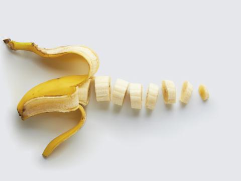 A peeled and sliced single banana isolated on a natural colored background.