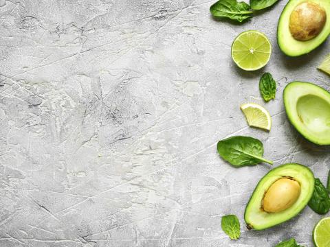 Avocado halves with lime slices and baby spinach leaves on a grey concrete,stone or slate background.Top view with copy space.; Shutterstock ID 525435586; Projectnummer: B09773 ; Uitgave: Libelle Lekker; Traffic: Rien Delvaux; Anders: /