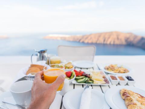European vacation healthy breakfast food selfie. POV of man drinking morning orange juice at resort restaurant. Table for two on outdoor hotel balcony caldera view on Oia Santorini, Greece, Europe.; Shutterstock ID 424776454; Projectnummer: B09773 ; Uitgave: Libelle Lekker; Traffic: Rien Delvaux; Anders: /