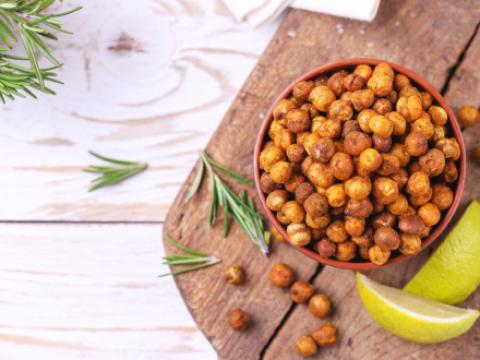 Traditional Indian cuisine. Roasted spicy chickpeas with lime and rosemary on rustic wooden background. Copyspace, top view.