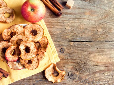 Organic apple cinnamon chips (slices) over rustic wooden background with copy space - healthy vegan vegetarian fruit snack or ingredient for cooking