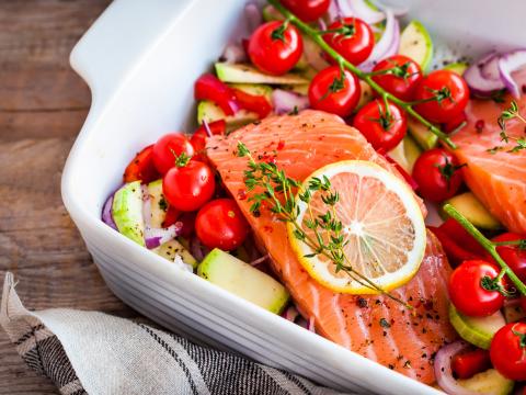 Raw fresh delicious salmon, cherry tomatoes, onion, zucchini, pepper and lemon in pan, ready to cook