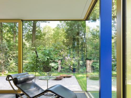 De leefruimte is volledig op de tuin georiënteerd, met glaspartijen van 16,5 meter lang. Gouden geanodiseerde raamprofielen omarmen de relaxte setting en de chaise longue van Le Corbusier.© Giulia Frigerio