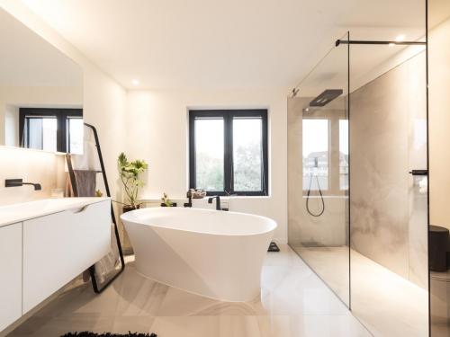 Zongekuste zandtinten en  een glazen doorkijkwand geven de badkamer een onmisbaar wellnessgevoel in huis.©  ARG Architecten