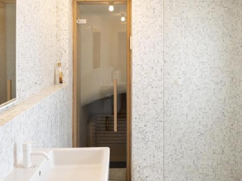 Zowel de badkamervloer als de muren zijn bezet met kleine mozaïektegels. Een minimalistisch geheel met de wittonen en sobere lichte kleur van de Poolse den gebruikt voor het badkamerschrijnwerk.