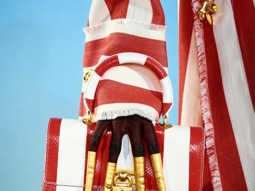 Gestreept staat hipHemdjurk met uitgerafelde boord en bijhorende tas in wit-rode strepen, van Schiaparelli (prijs op aanvraag).