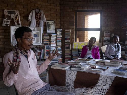 Founder of the Soweto Book Cafe, Thami Mazibuko, gestures in his home in Soweto on April 5, 2022. - In Thami Mazibuko's childhood home, the 36-year-old has turned the upper level into a bookstore and library, seeded with 30 of his own books, now overflowing with hundreds of donations.After he finished school, he left Soweto and moved into the formerly white suburbs of Johannesburg, where he stayed with relatives who were artists, with a home full of books.He developed an insatiable appetite for reading, even bring books into the reggae club where liked to listen to music.When he decided to move back home, he brought his growing personal collection with him.So began the Soweto Book Cafe, officially founded in 2018. (Photo by EMMANUEL CROSET / AFP)