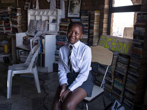 Anele Ndlovu, 14, one of the book club's regular visitors, poses for a portrait at the Soweto Book Cafe in Soweto on April 5, 2022. - In Thami Mazibuko's childhood home, the 36-year-old has turned the upper level into a bookstore and library, seeded with 30 of his own books, now overflowing with hundreds of donations.
After he finished school, he left Soweto and moved into the formerly white suburbs of Johannesburg, where he stayed with relatives who were artists, with a home full of books.
He developed an insatiable appetite for reading, even bring books into the reggae club where liked to listen to music.
When he decided to move back home, he brought his growing personal collection with him.
So began the Soweto Book Cafe, officially founded in 2018. (Photo by EMMANUEL CROSET / AFP)