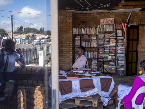 The founder of the Soweto Book Cafe, Thami Mazibuko (C), looks on in his home in Soweto on April 5, 2022. - In Thami Mazibuko's childhood home, the 36-year-old has turned the upper level into a bookstore and library, seeded with 30 of his own books, now overflowing with hundreds of donations.After he finished school, he left Soweto and moved into the formerly white suburbs of Johannesburg, where he stayed with relatives who were artists, with a home full of books.He developed an insatiable appetite for reading, even bring books into the reggae club where liked to listen to music.When he decided to move back home, he brought his growing personal collection with him.So began the Soweto Book Cafe, officially founded in 2018. (Photo by EMMANUEL CROSET / AFP)