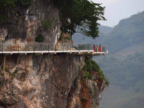 Visitors stand on the walkway section of the Bach Long glass bridge in Moc Chau district in Vietnam's Son La province on April 29, 2022. - Vietnam launched a new attraction for tourists -- with a head for heights -- on April 29 with the opening of a glass-bottomed bridge suspended some 150 metres above a lush, jungle-clad gorge. (Photo by Nhac NGUYEN / AFP)