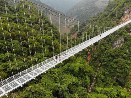 This aerial photo shows the newly constructed Bach Long glass bridge in Moc Chau district in Vietnam's Son La province on April 29, 2022. - Vietnam launched a new attraction for tourists -- with a head for heights -- on April 29 with the opening of a glass-bottomed bridge suspended some 150 metres above a lush, jungle-clad gorge. (Photo by Nhac NGUYEN / AFP)