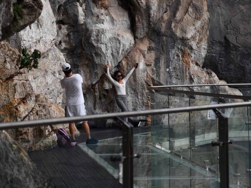Visitors pose for photos on the walkway section of the Bach Long glass bridge in Moc Chau district in Vietnam's Son La province on April 29, 2022. - Vietnam launched a new attraction for tourists -- with a head for heights -- on April 29 with the opening of a glass-bottomed bridge suspended some 150 metres above a lush, jungle-clad gorge. (Photo by Nhac NGUYEN / AFP)