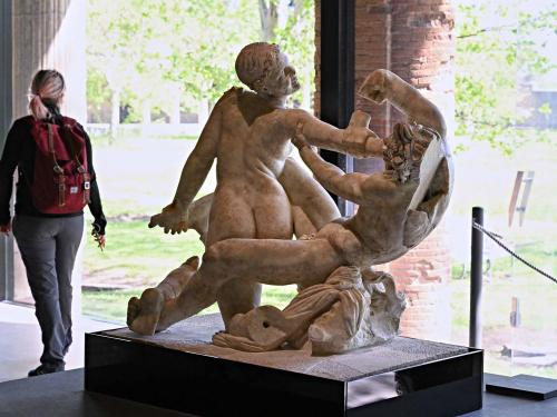 A vistor walks next to a "Satyr and hermaphrodite" sculpture, in Pompeii's site of a new exhibition entitled "Art and sensuality in the houses of Pompeii" on art and sexuality in the ancient city, where sculptures and paintings of breasts and buttocks abounded, on April 28, 2022. - Raunchy scenes may redden faces at a new exhibition in Pompeii on art and sexuality in the ancient Roman city, where sculptures and paintings of breasts and buttocks abounded. Archaeologists excavating the city, which was destroyed by the eruption of nearby Vesuvius in 79 AD, were initially startled to discover erotic images everywhere, from garden statues to ceiling frescos. (Photo by Andreas SOLARO / AFP)