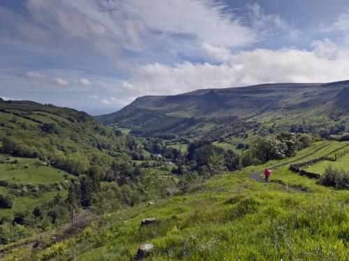 Here is the view of Glenariff from the Glenariff Forest Park on a June morning.  An anonymous human figure walking away provides scale and interest.  Glenariff is a valley of County Antrim, Northern Ireland.  Known for lush farmland, this glacially carved glen has a mouth on the North Channel of the Irish Sea at the town of Waterfoot.