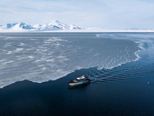 This aerial view image taken on May 3, 2022 shows the Kvitbjorn (Polar Bear, in Norwegian), a hybrid touristic boat, combining a diesel motor and electric batteries, as it makes its way in the sea ice in the Borebukta Bay, located at the northwestern side of Isfjorden, in Svalbard Archipelago, northern Norway. (Photo by Jonathan NACKSTRAND / AFP)