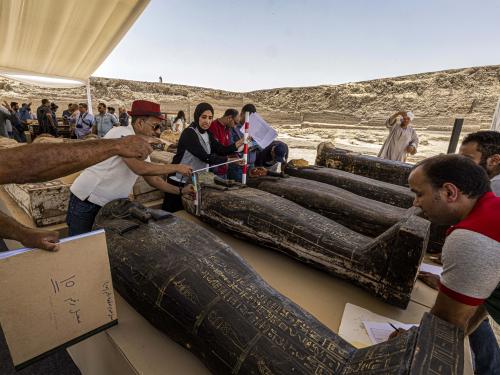 Archaeologists measure the length to register one of the sarcophaguses found in a cache dating to the Egyptian Late Period (around the fifth century BC), discovered by a mission headed by Egypt's Supreme Council of Antiquities, at the Bubastian cemetery at the Saqqara necropolis, southwest of Egypt's capital on May 30, 2022. - Egypt on May 30 unveiled a cache of 150 bronze statues depicting various gods and goddesses including "Bastet, Anubis, Osiris, Amunmeen, Isis, Nefertum and Hathor," along with 250 sarcophagi at the Saqqara archaeological site south of Cairo, the latest in a series of discoveries in the area. (Photo by Khaled DESOUKI / AFP)