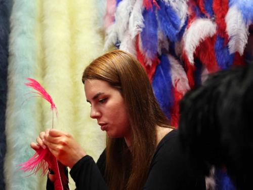 An assistant of Dominique De Roo, official feather craftsman of the Lido cabaret, works on a feather costume inside the workshop, in Paris, on June 1, 2022. - The Lido cabaret, an institution for Parisian night life since 1889, is set to lay off 157 of 184 employees, including its "Bluebell girls" troupe of dancers, announced the new owner, French hotels giant Accor. (Photo by Thomas COEX / AFP)