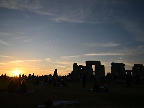 The sun sets behind the stones at Stonehenge, near Amesbury, in Wiltshire, southern England on June 20, 2022, on the eve of a festival, dating back thousands of years, that will celebrate the longest day of the year when the sun will be at its maximum elevation. - The stone monument -- carved and constructed at a time when there were no metal tools -- symbolises Britain's semi-mythical pre-historic period, and has spawned countless legends. (Photo by Justin TALLIS / AFP)