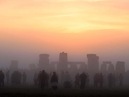 Revellers celebrate the Summer Solstice as the sun rises at Stonehenge, near Amesbury, in Wiltshire, southern England on June 21, 2022, in a festival, which dates back thousands of years, celebrating the longest day of the year when the sun is at its maximum elevation. - The stone monument -- carved and constructed at a time when there were no metal tools -- symbolises Britain's semi-mythical pre-historic period, and has spawned countless legends. (Photo by Justin TALLIS / AFP)