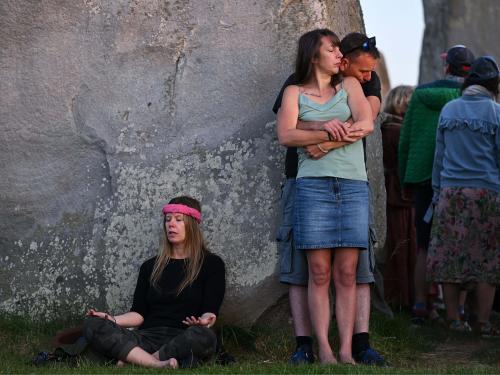 Revelers interact with the stone monument as the sun sets behind the stones at Stonehenge, near Amesbury, in Wiltshire, southern England on June 20, 2022, on the eve of a festival, dating back thousands of years, that will celebrate the longest day of the year when the sun will be at its maximum elevation. - The stone monument -- carved and constructed at a time when there were no metal tools -- symbolises Britain's semi-mythical pre-historic period, and has spawned countless legends. (Photo by Justin TALLIS / AFP)
